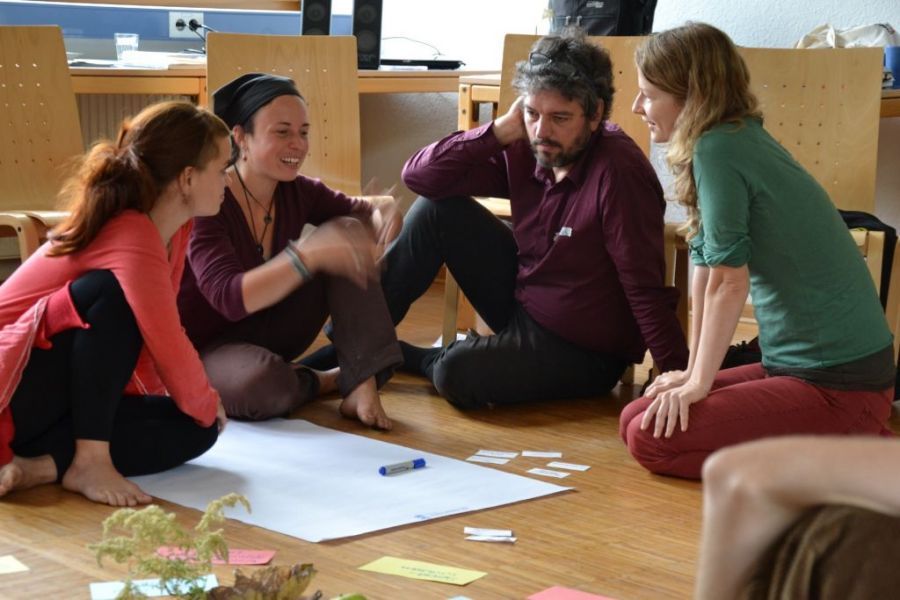 Gruppe sitzt vor Flipchart und diskutiert